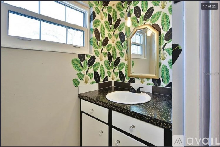 A bathroom with a leaf patterned wallpaper and a white sink.