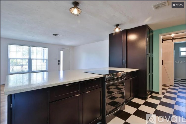 A kitchen with black cabinets and a checkered floor.