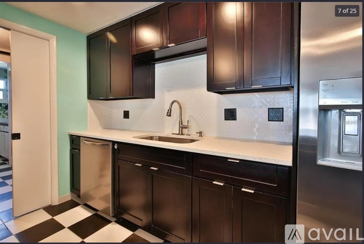 A kitchen with black cabinets and a checkered floor.