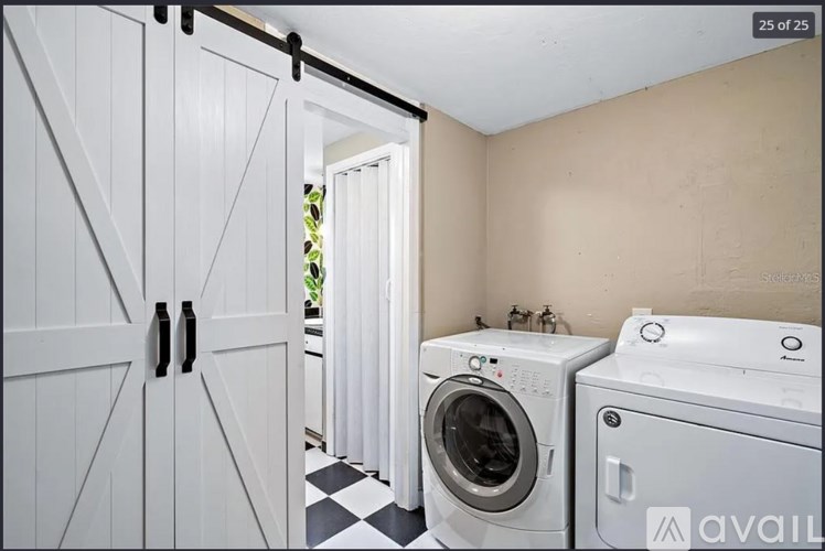 A laundry room with a washer and dryer, a black and white checkered floor, and a white door.