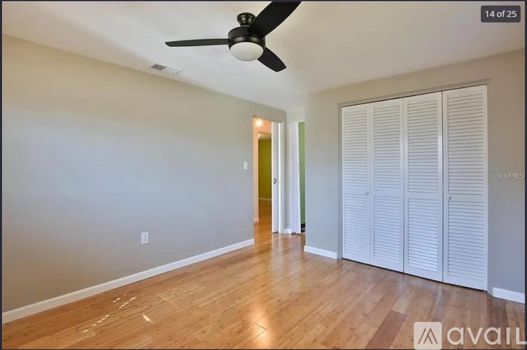 A room with a ceiling fan and wooden flooring.