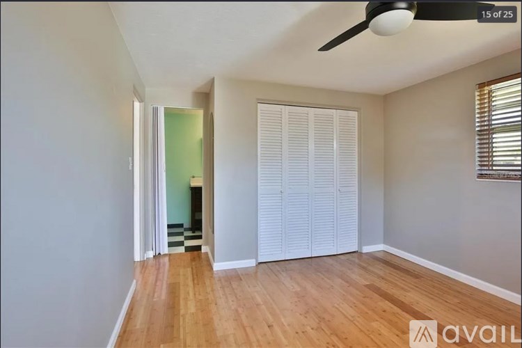 A room with a fan and a window with blinds.