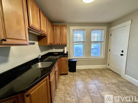 A kitchen with wooden cabinets and black countertops.