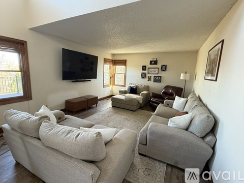 A living room with a grey couch and a flat screen TV mounted on the wall.