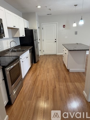 A kitchen with wooden floors and white cabinets.