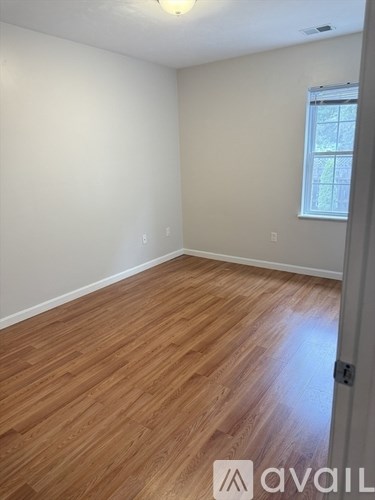 A room with wooden flooring and a window.