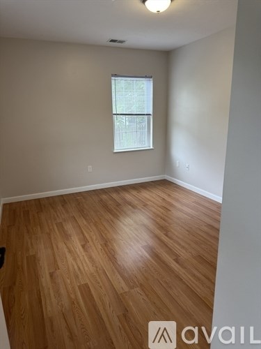 A room with wooden flooring and a window.
