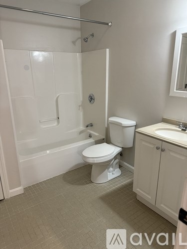 A white toilet sits in a bathroom next to a sink and a bathtub.
