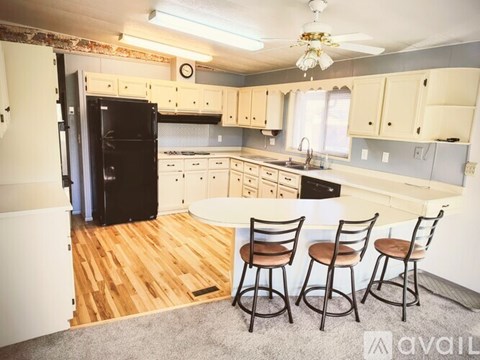 A kitchen with a black fridge and wooden floors.