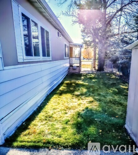 A house with a white siding and a green lawn.