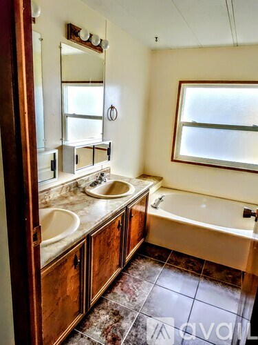 A bathroom with a tub, sink and mirror.