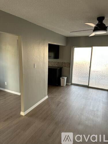 A room with a fan, a fireplace, and a trash can.