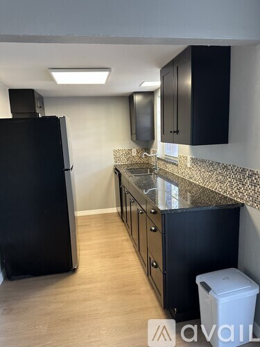 A kitchen with black cabinets and a black fridge.