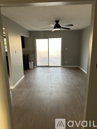 A room with a ceiling fan and sliding glass doors.