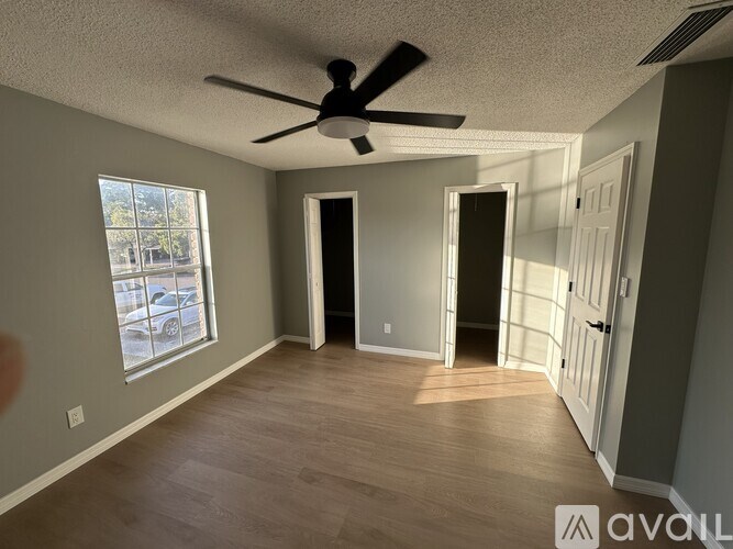 A room with a ceiling fan and wooden flooring.