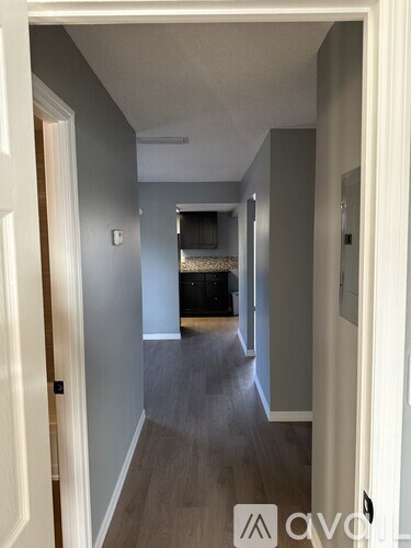 A hallway with a door on the left and a bedroom at the end.