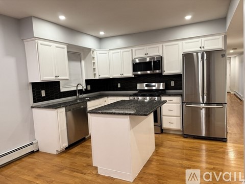 A kitchen with white cabinets and black countertops.