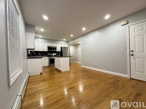 A spacious kitchen with wooden flooring and white cabinetry.