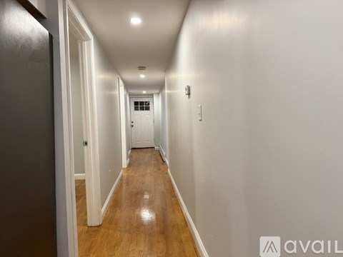 A long hallway with wooden floors and white walls.