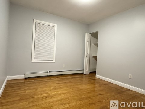 A room with wooden flooring and a window with blinds.