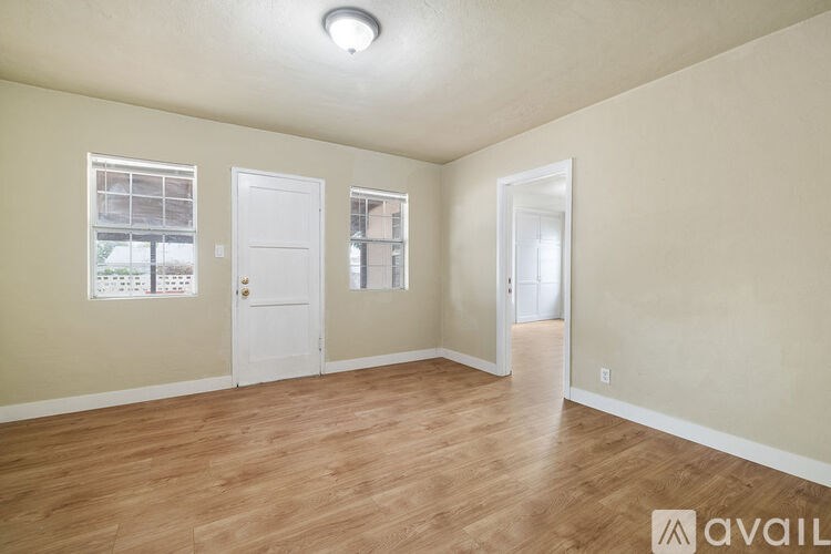A room with wooden flooring and three doors.