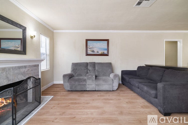 A living room with a grey couch, a grey armchair, and a fireplace.