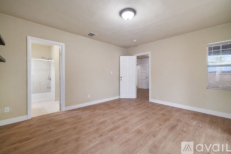 A room with wooden flooring and a window on the right side.