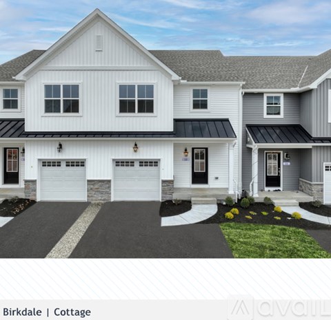 A two-story white house with a black roof and a garage.