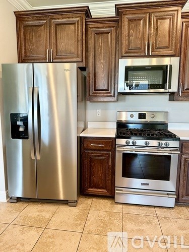 A kitchen with a stainless steel refrigerator, a stainless steel oven, and wooden cabinets.