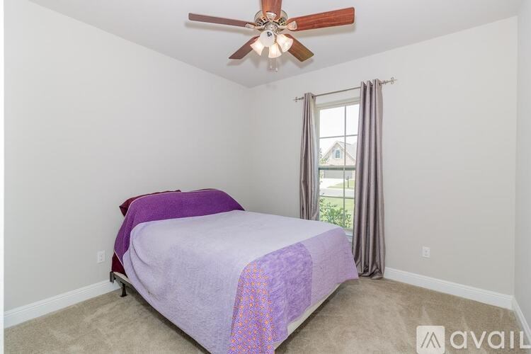 A bedroom with a bed covered in a purple blanket.