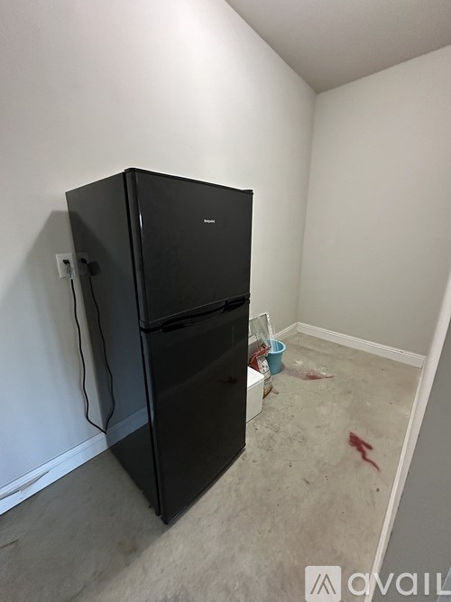 A black fridge in a room with white walls.