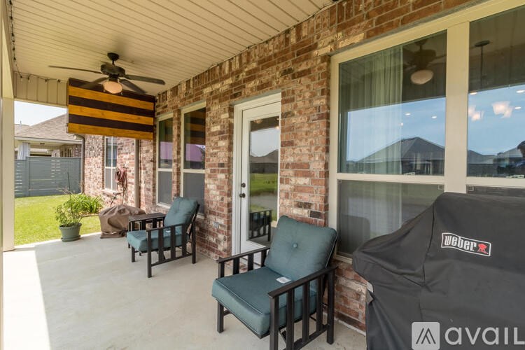 A covered patio with a ceiling fan and two chairs.