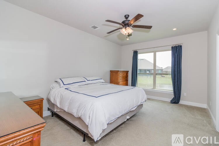 A bedroom with a bed, dresser, and window.