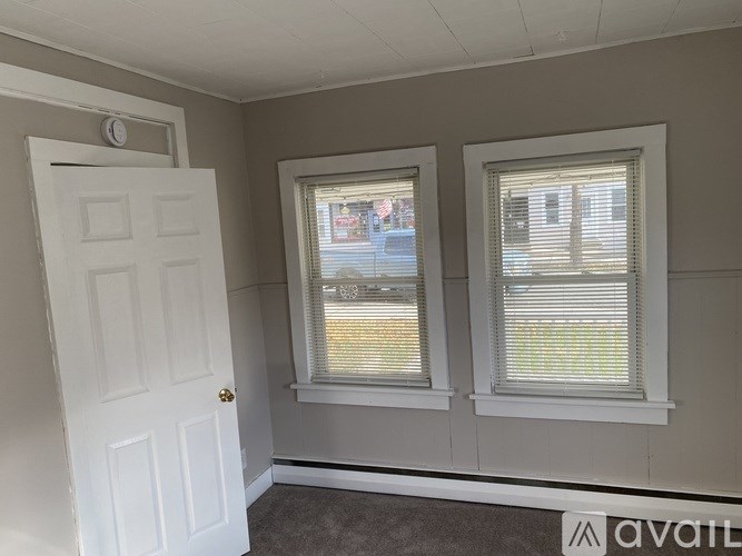 A room with a white door and two windows with blinds.