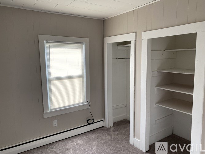 A room with a window and an open closet door.