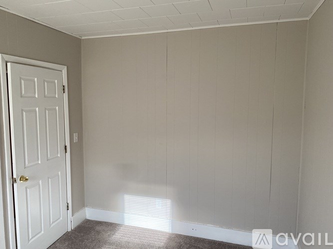 A room with a white door and a carpeted floor.