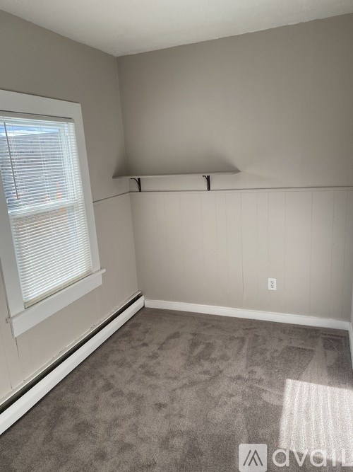 A room with a carpeted floor and a window with blinds.