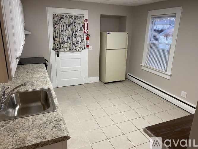 A kitchen with a sink, refrigerator, and a window.