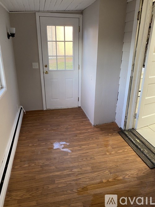 A room with a white door and wooden floor.