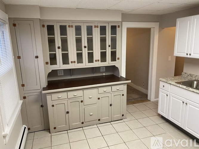 A kitchen with white cabinets and a brown countertop.