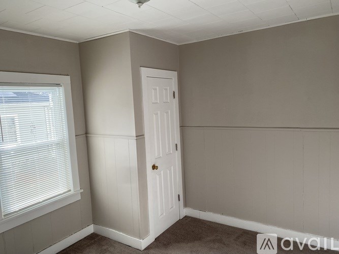 A room with a door, window, and carpeted floor.