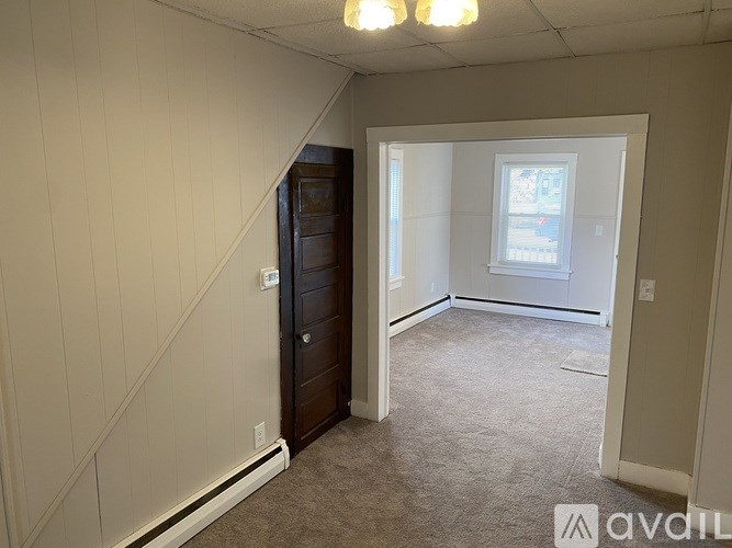 A room with a carpeted floor and a window with a white frame.