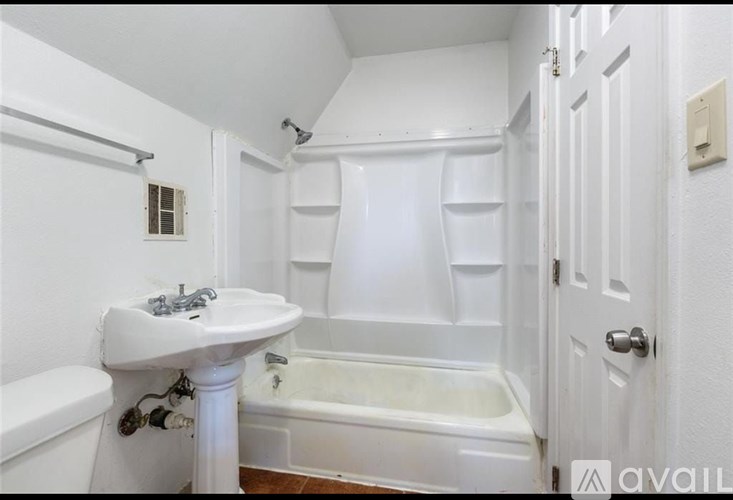 A white bathroom with a tub, sink, and toilet.