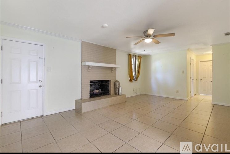 A living room with a fireplace and a ceiling fan.