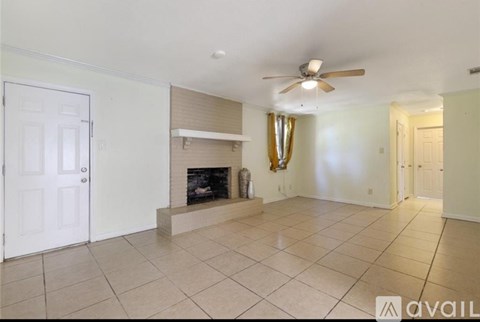 A living room with a fireplace and a ceiling fan.