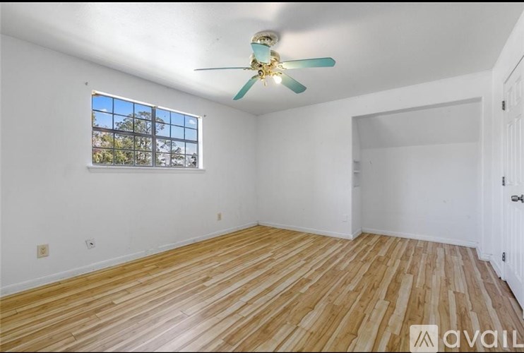 A room with a ceiling fan and wooden flooring.