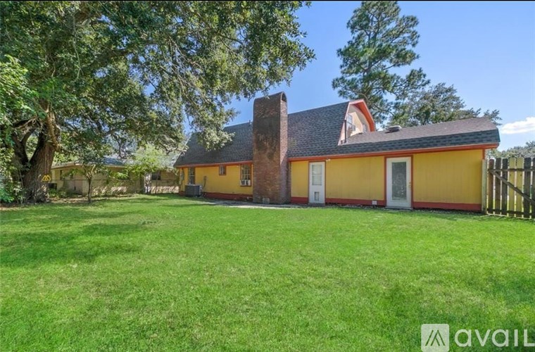 A yellow house with a chimney and a green lawn in front.