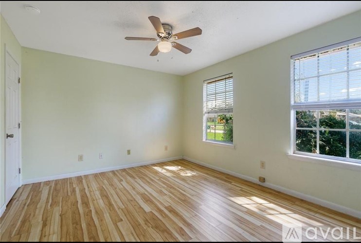 A room with a ceiling fan and wooden flooring.