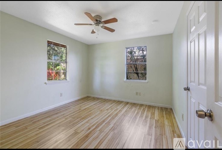 A room with a ceiling fan and wooden flooring.