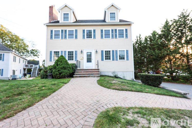 A white house with a brick pathway leading to the front door.